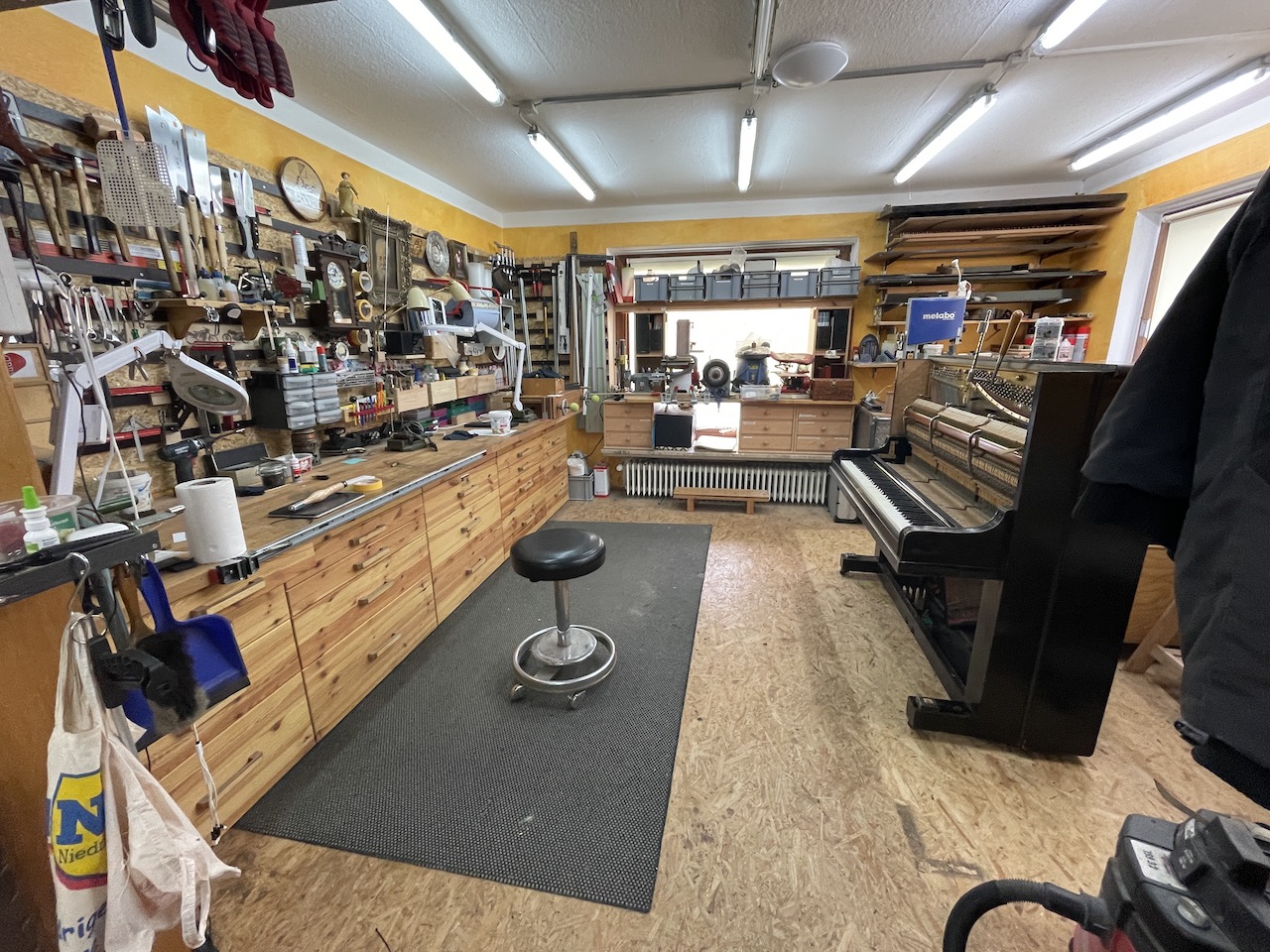 Blick durch die Werkstatt mit Klavier und Werkbank